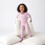 Child wearing pink pajamas with a white pillow background