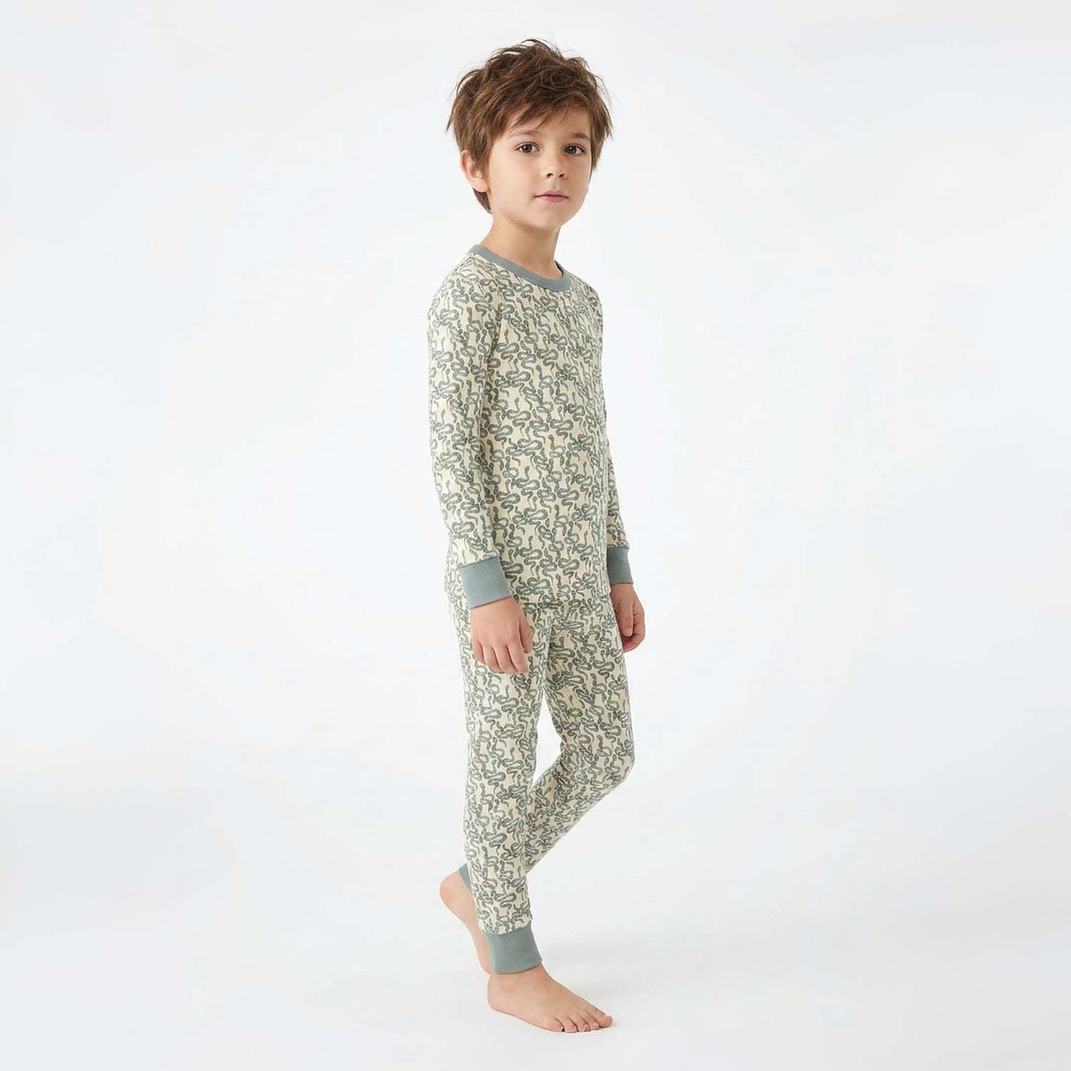 Child wearing a green snake patterned pajama set on a white background