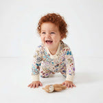 Baby in a floral onesie with a toy on a white background