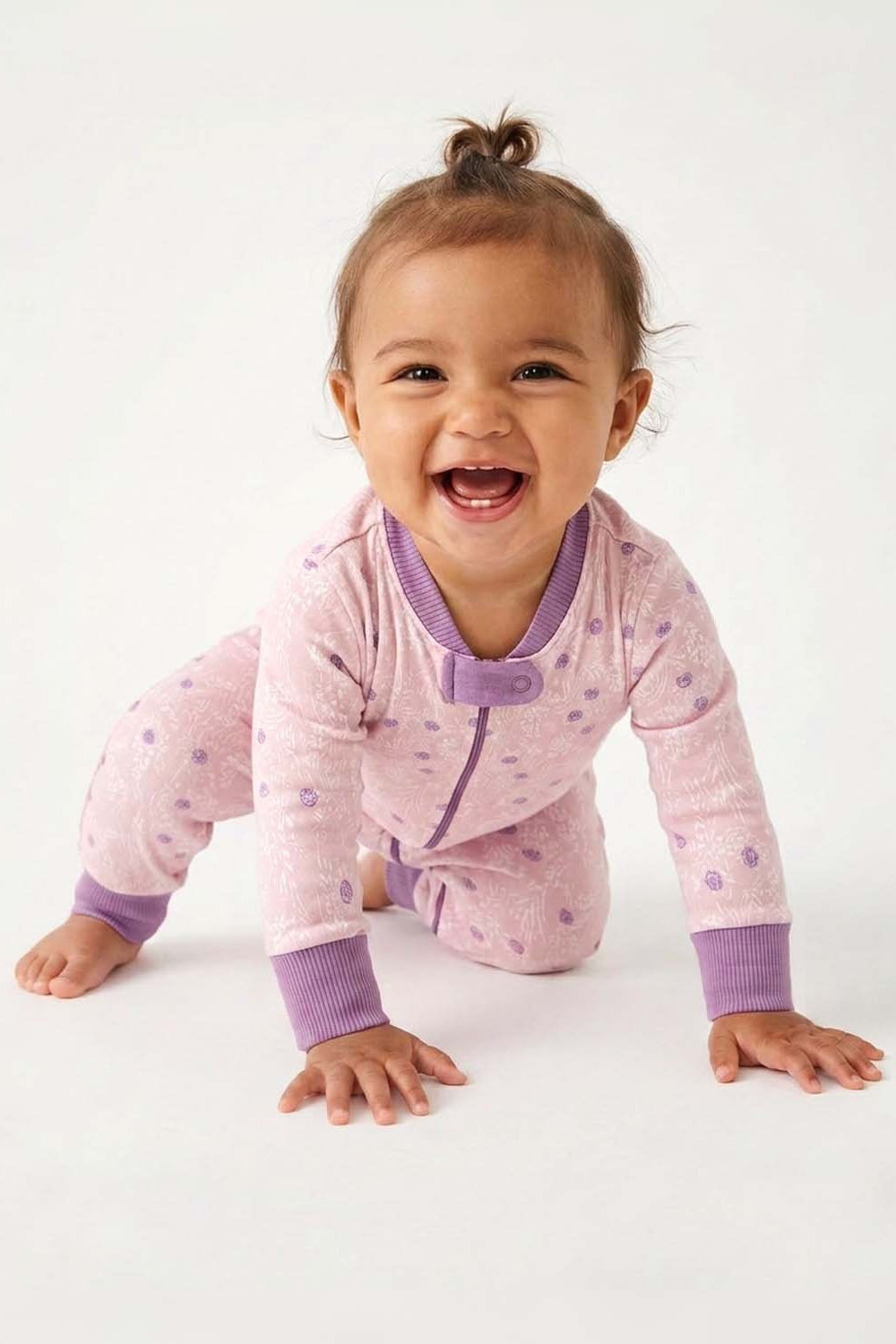 Baby in a pink and purple outfit with a white background