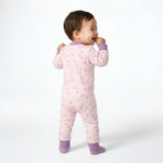 Baby wearing a pink onesie with purple accents on a white background