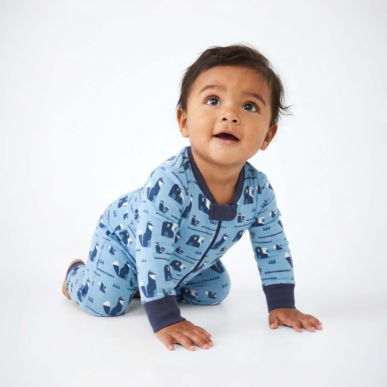 Baby wearing a blue pajama with animal pattern on a white background