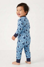 Baby standing wearing a blue pajama with animal pattern on a white background