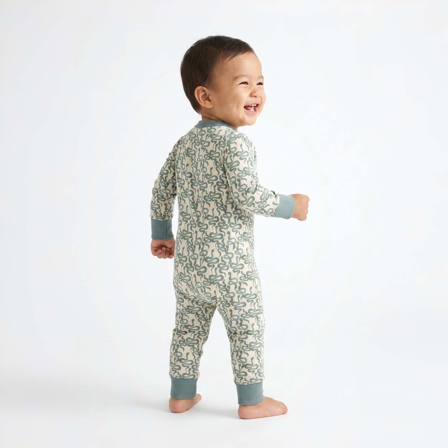 Child wearing a snake print onesie on a white background