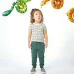Child wearing a snake print shirt and green pants with snakes in the background