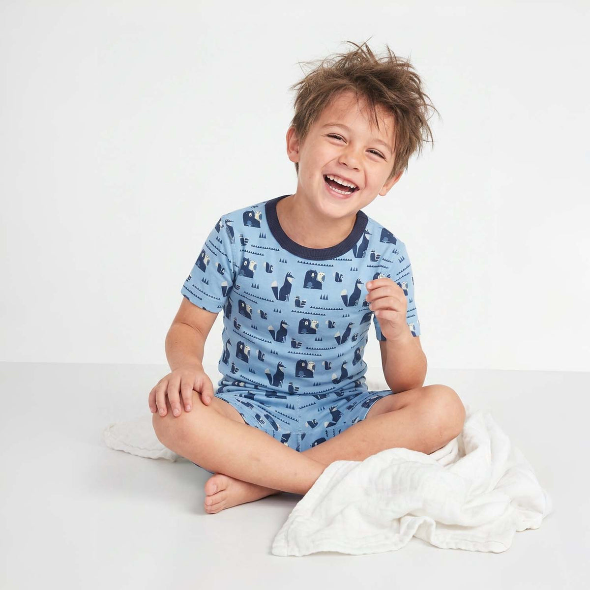 Child wearing blue pajamas with animal pattern on a white background