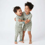 Two children wearing matching green snake pajamas on a white background