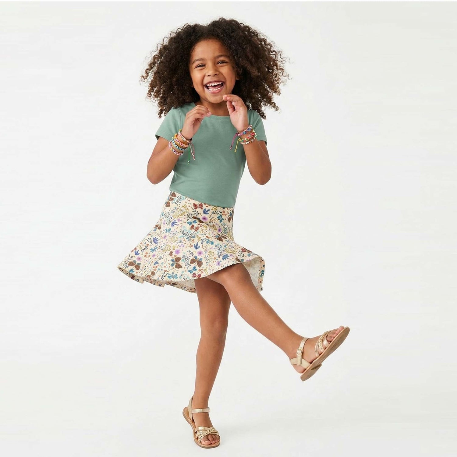 Young girl in a green shirt and floral skirt on a white background