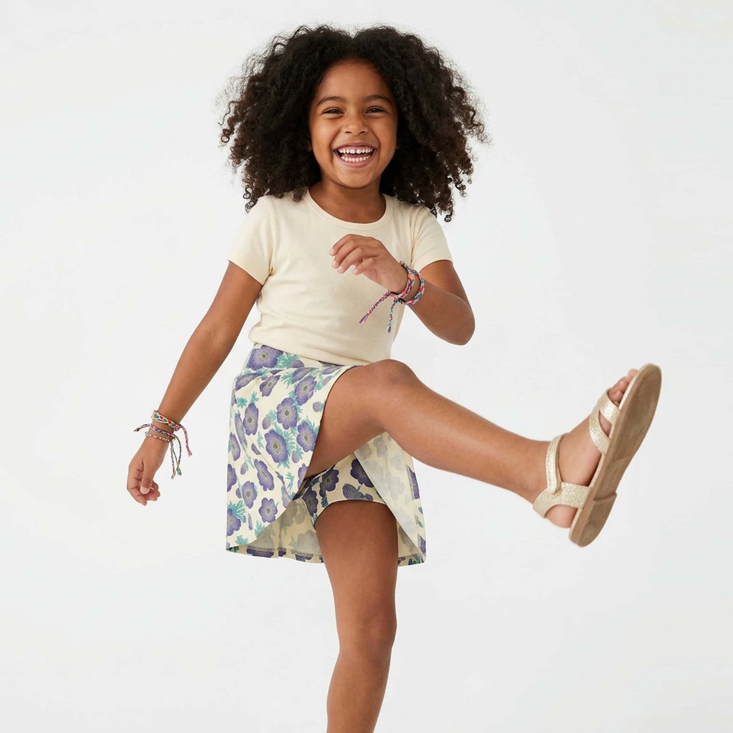 Young girl wearing a floral skirt with built-in short and ivory shirt on a white background