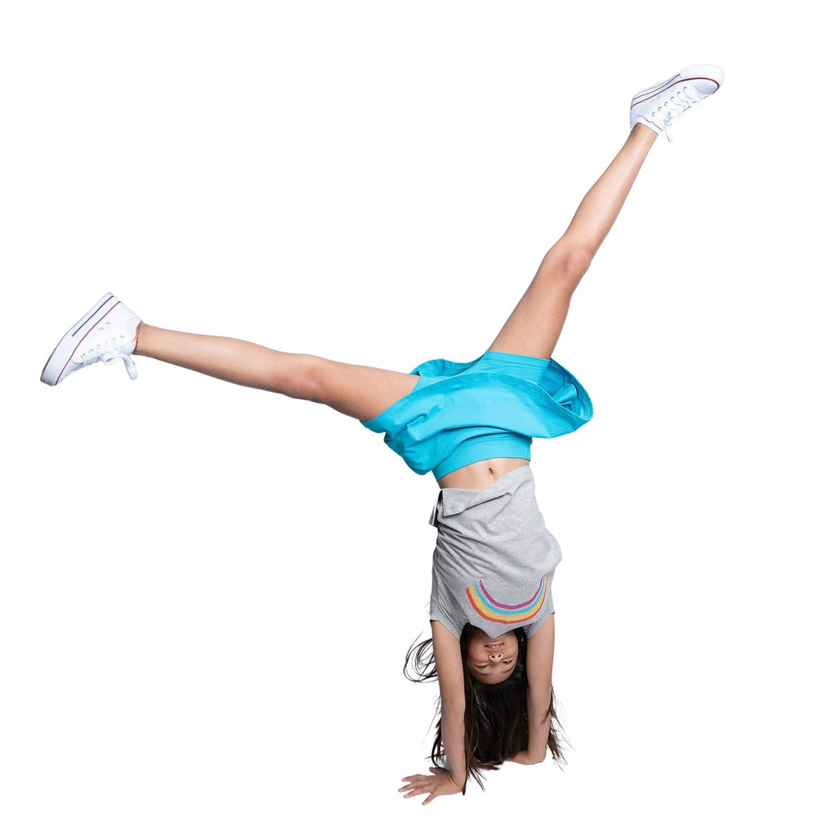 girl with long hair doing a cartwheel wearing a turquoise skort and gray short with a rainbow print