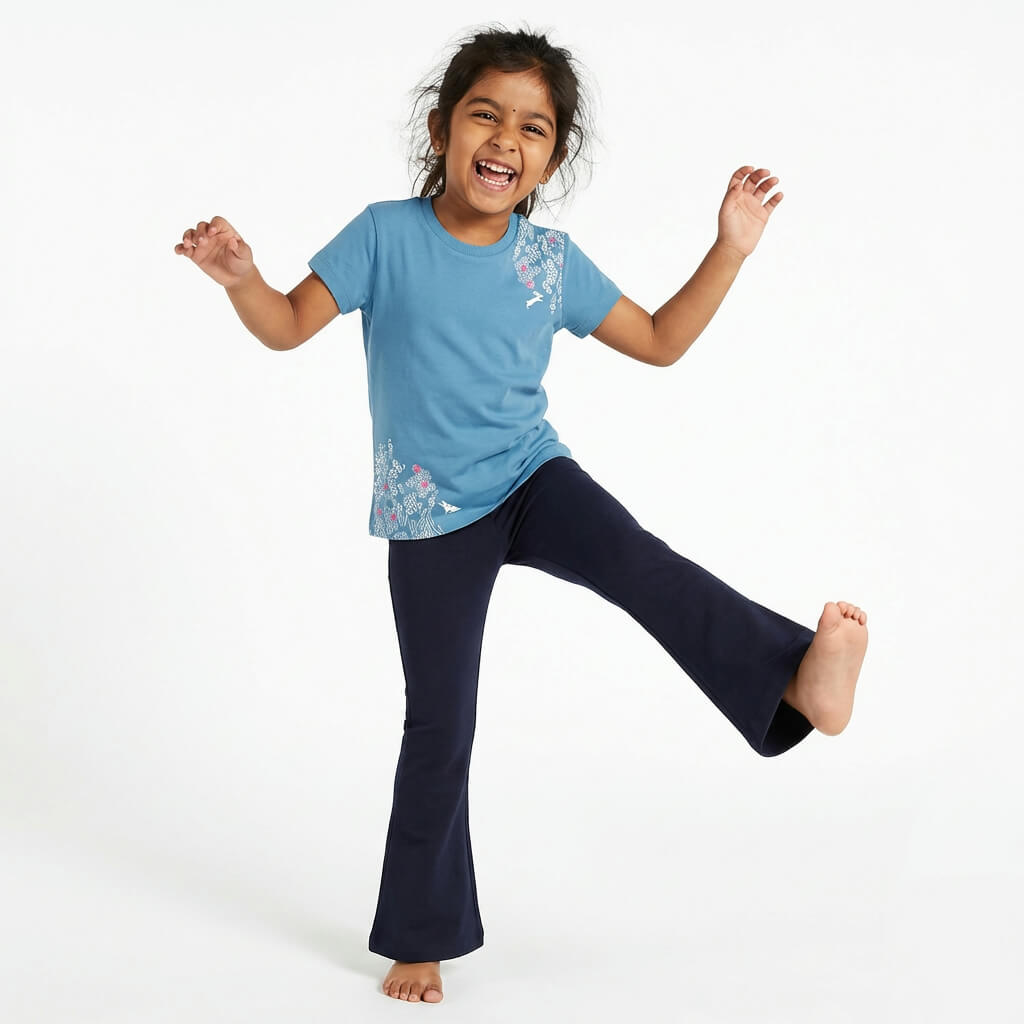 Young girl wearing a Mightly 100% organic cotton graphic tee with a pink and white print featuring flowers and bunnies and navy blue pants.