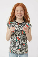 Young girl wearing a leopard print shirt with flower patterns on a white background