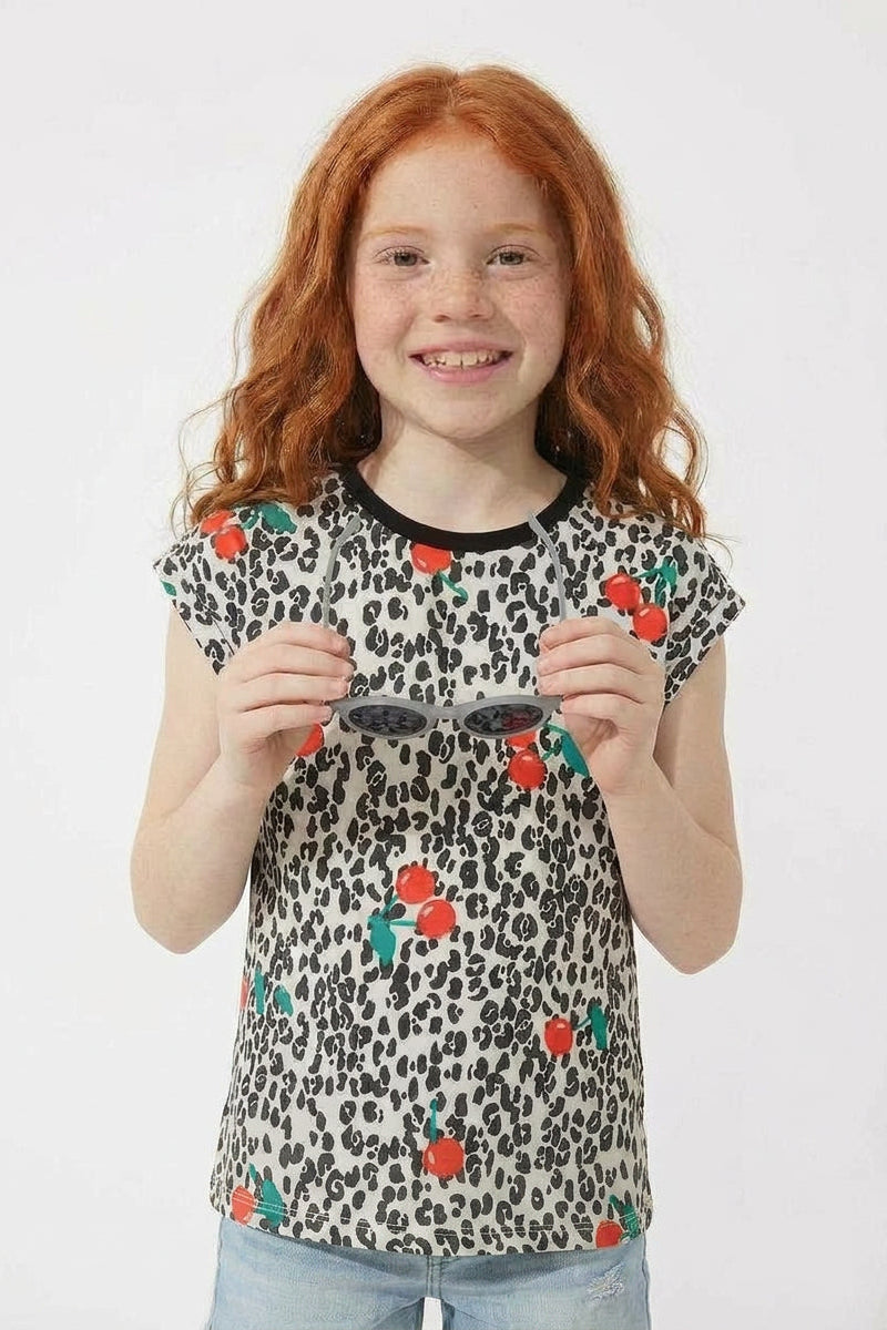 Young girl wearing a leopard print shirt with flower patterns on a white background