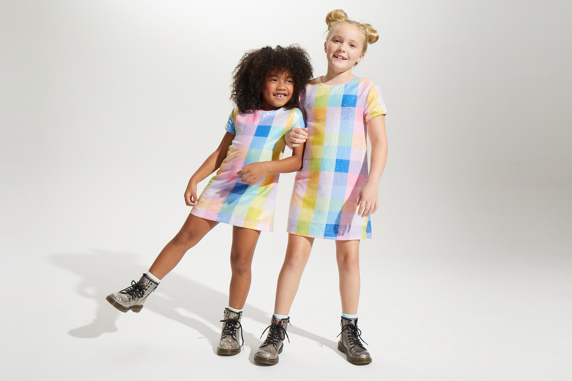 Two children wearing colorful checkered dresses on a white background